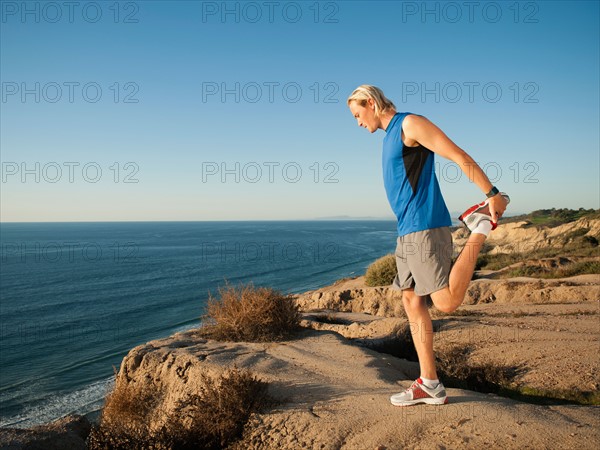 USA, California, San Diego, Man stretching at sea coast.