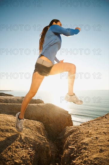 USA, California, San Diego, Woman jogging along sea coast.