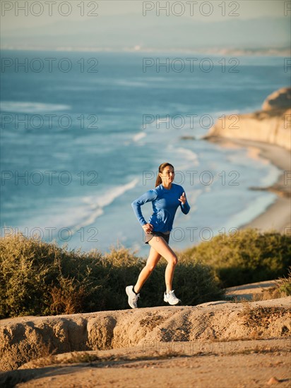 USA, California, San Diego, Woman jogging along sea coast.