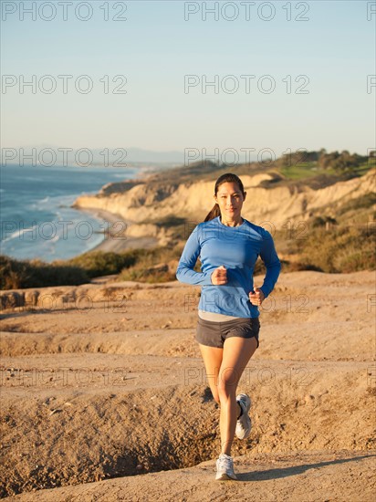 USA, California, San Diego, Woman jogging along sea coast.