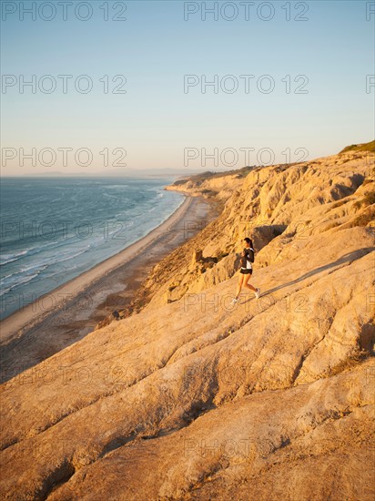 USA, California, San Diego, Woman jogging along sea coast.