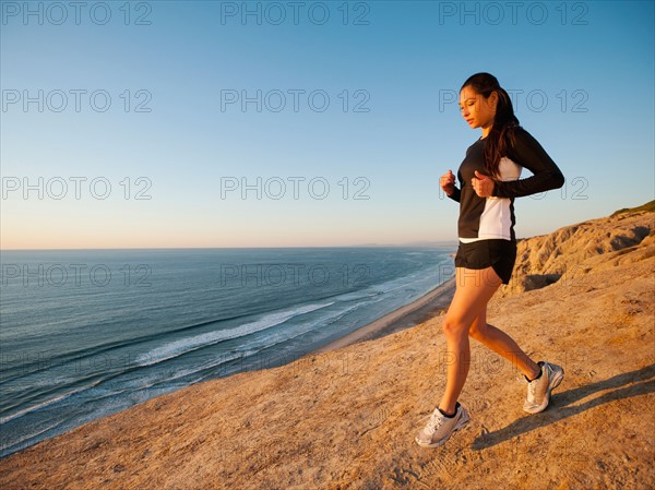 USA, California, San Diego, Woman jogging along sea coast.