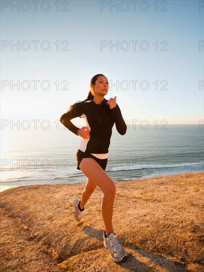 USA, California, San Diego, Woman jogging along sea coast.