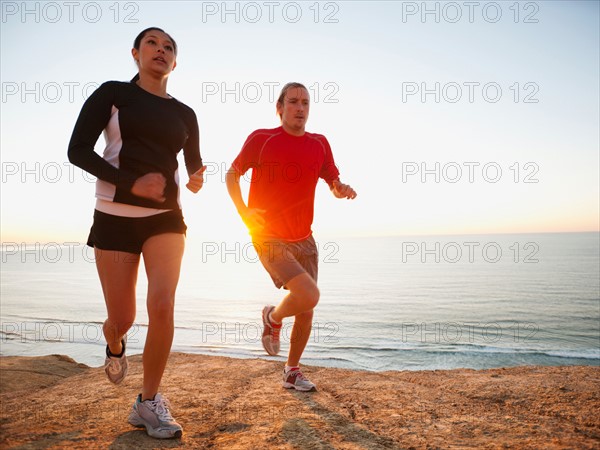 USA, California, San Diego, Man and woman jogging along sea coast.