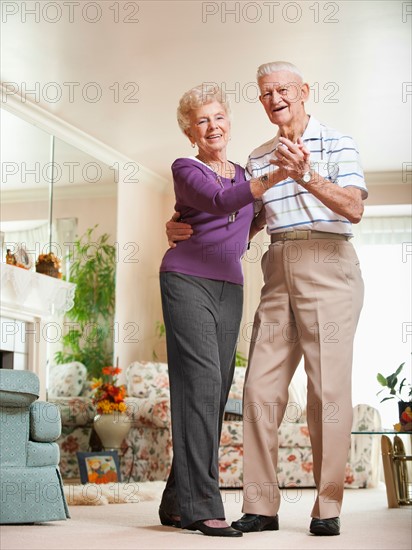 Senior couple dancing at home.