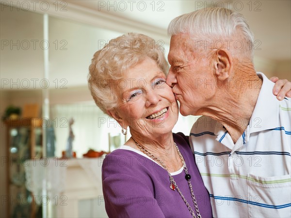 Senior man kissing woman.