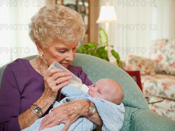 Senior woman giving milk to grandson (2-5 months).