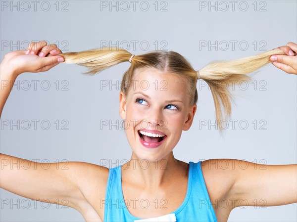 Studio portrait of young woman with hand in hair. Photo : Yuri Arcurs