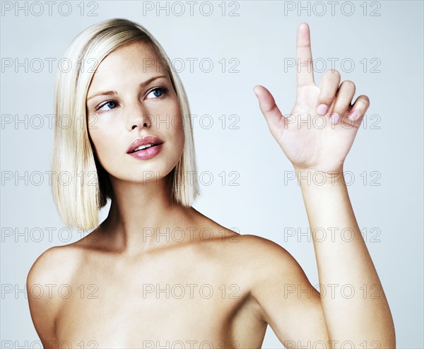 Young woman touching screen, studio shot. Photo : Yuri Arcurs