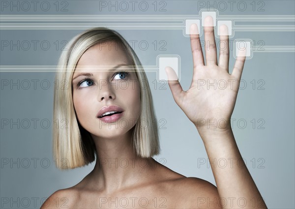 Young woman with hand on touchscreen reading her fingerprints. Photo : Yuri Arcurs