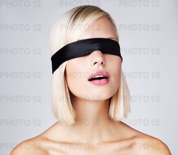 Young woman wearing blindfold, studio shot. Photo : Yuri Arcurs