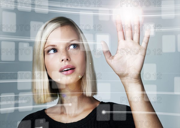 Young woman using futuristic touchscreen, studio shot. Photo : Yuri Arcurs