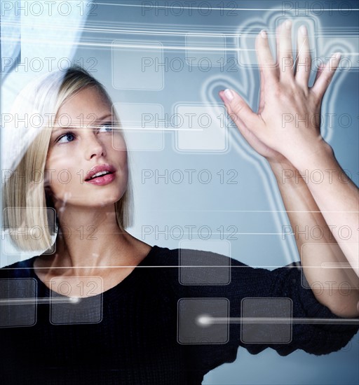 Young woman using futuristic touchscreen, studio shot. Photo : Yuri Arcurs