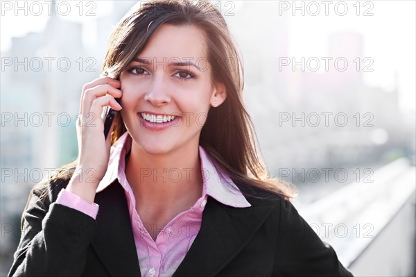 Smiling young businesswoman talking via mobile. Photo : Take A Pix Media