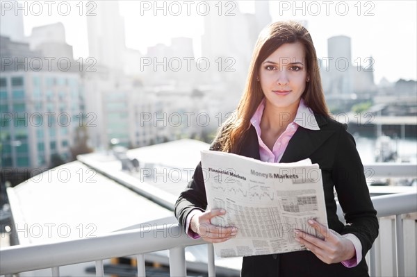 USA, Seattle, Young businesswoman reading newspaper. Photo : Take A Pix Media