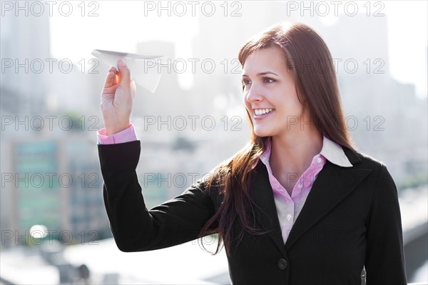 USA, Seattle, Smiling businesswoman holding paper plane. Photo : Take A Pix Media