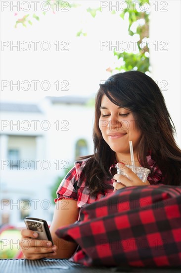 Young woman using phone in outdoor cafe. Photo : Sarah M. Golonka