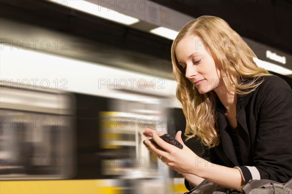 USA, California, Los Angeles, Woman sending text messages on subway station. Photo : Sarah M. Golonka