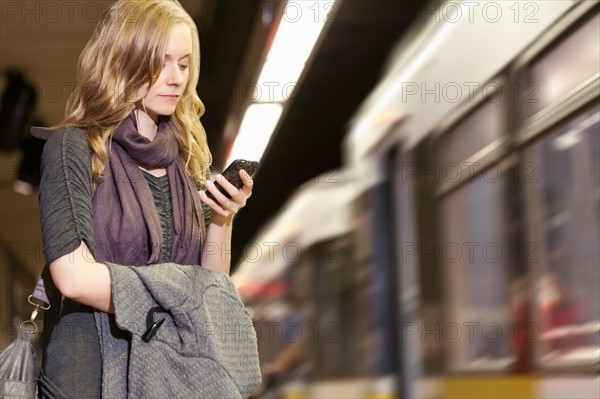 USA, California, Los Angeles, Woman sending text messages on subway station. Photo : Sarah M. Golonka