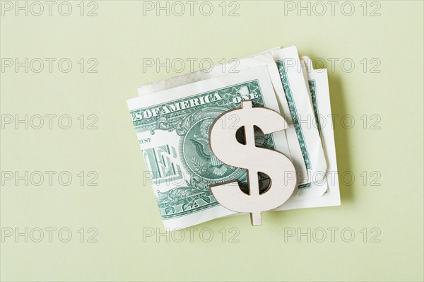 Dollar banknotes in dollar symbol shaped money clip, studio shot. Photo : Kristin Lee