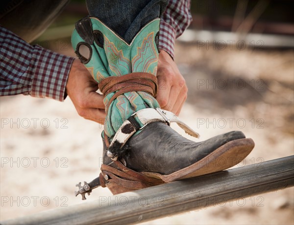 Close-up of cowboy tying shoe. Photo : Mike Kemp