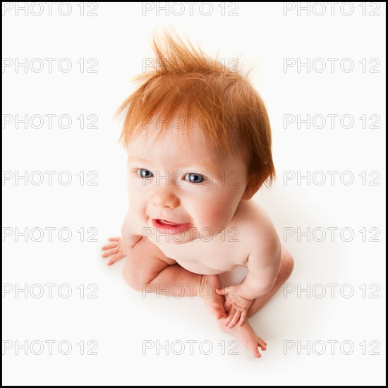 High angle view of baby girl (6-11 months) sitting, studio shot. Photo : Mike Kemp