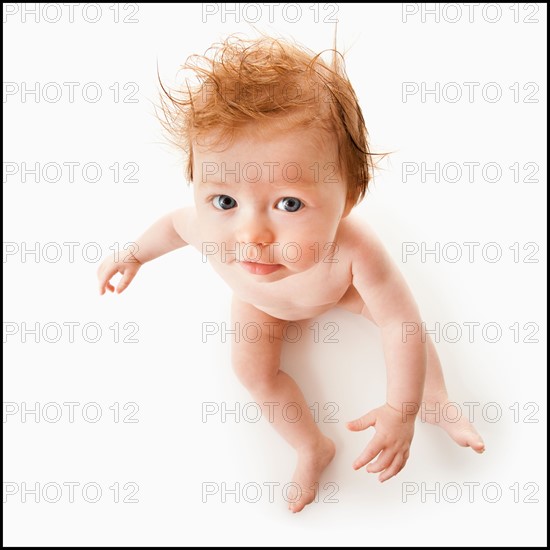 High angle view of baby girl (6-11 months) sitting, studio shot. Photo : Mike Kemp