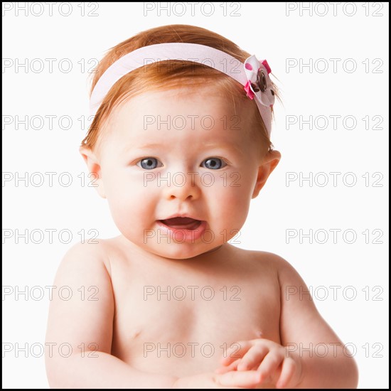 Portrait of baby girl (6-11 months) smiling, studio shot. Photo : Mike Kemp