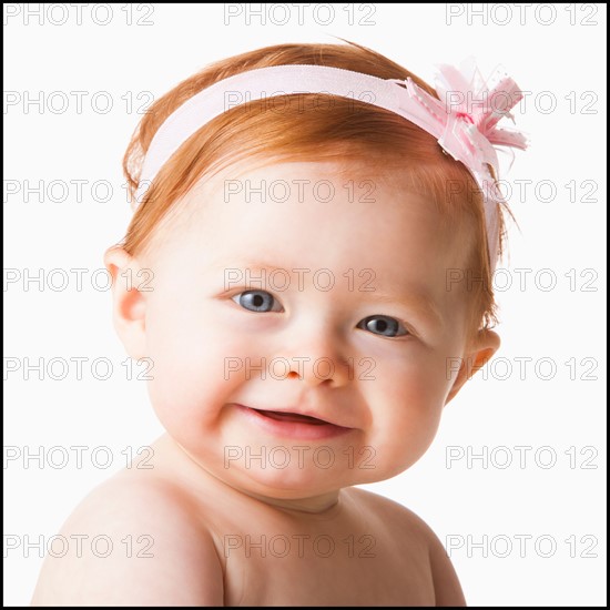 Portrait of baby girl (6-11 months) smiling, studio shot. Photo : Mike Kemp