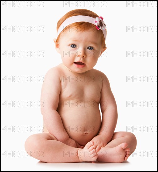 Portrait of baby girl (6-11 months) smiling, studio shot. Photo : Mike Kemp