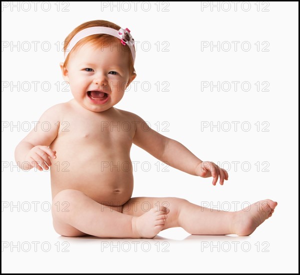 Portrait of baby girl (6-11 months) laughing, studio shot. Photo : Mike Kemp