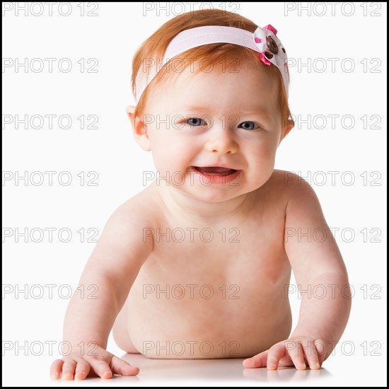 Portrait of baby girl (6-11 months) smiling, studio shot. Photo : Mike Kemp