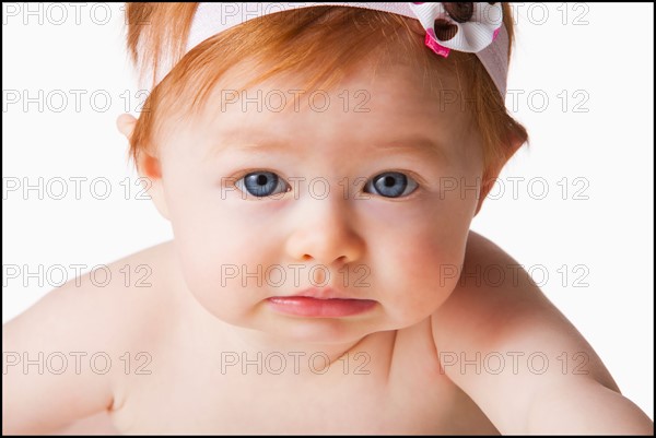 Portrait of baby girl (6-11 months) looking at camera, studio shot. Photo : Mike Kemp