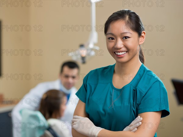 Portrait of dentist, dentist and patient in background. Photo : Dan Bannister