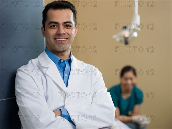 Portrait of dentist, dentist and patient in background. Photo : Dan Bannister