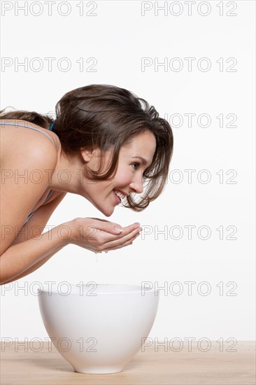 Portrait of woman washing face, studio shot. Photo : Jan Scherders