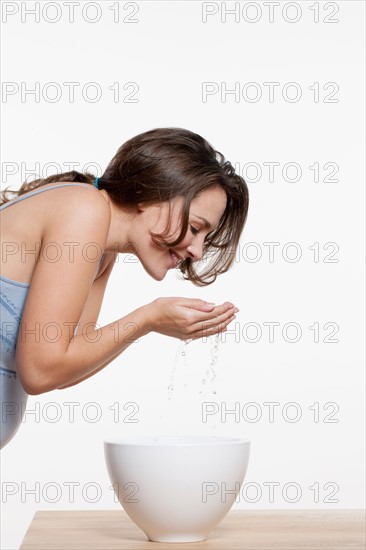 Portrait of woman washing face, studio shot. Photo : Jan Scherders