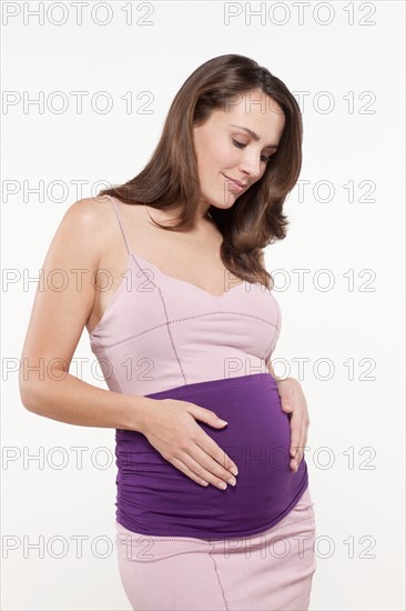 Portrait of pregnant woman in pink dress, studio shot. Photo : Jan Scherders