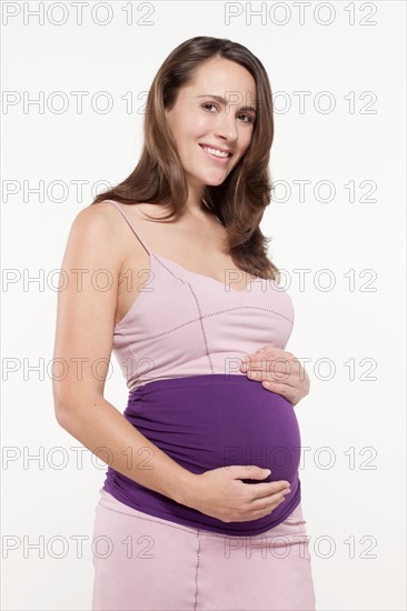 Portrait of pregnant woman in pink dress, studio shot. Photo : Jan Scherders