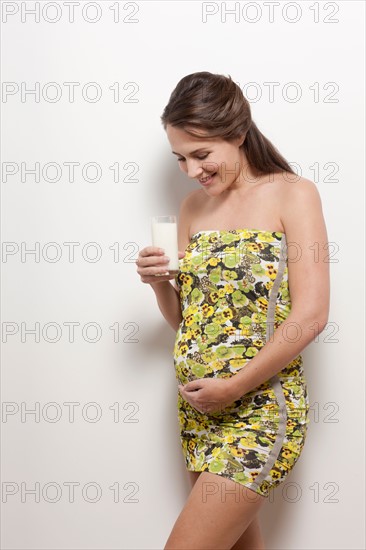 Portrait of pregnant woman holding glass of milk, studio shot. Photo : Jan Scherders