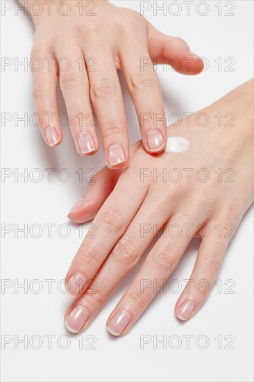 Close up of woman's hands applying moisturizer, studio shot. Photo : Jan Scherders