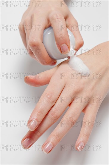 Close up of woman's hands applying moisturizer, studio shot. Photo : Jan Scherders