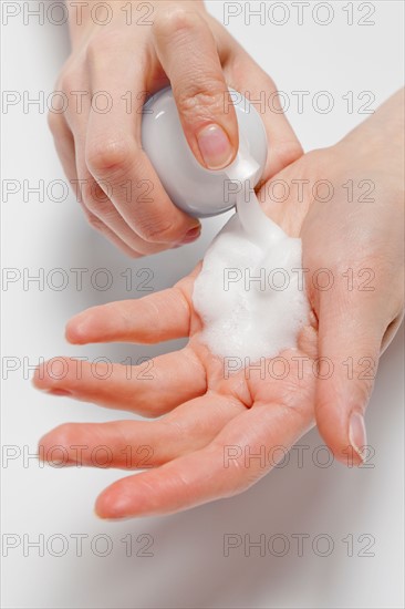 Close up of woman's hands applying moisturizer, studio shot. Photo : Jan Scherders