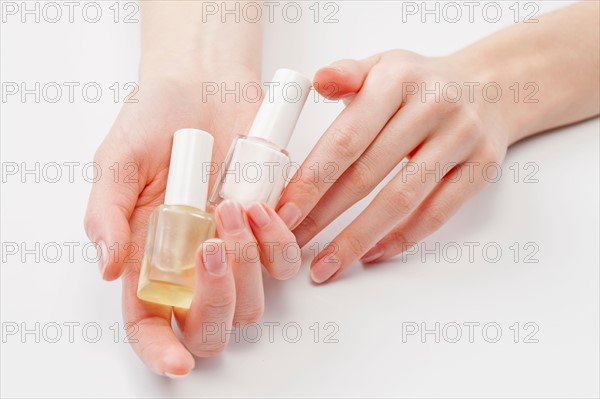 Close up of woman's hands holding nail polish, studio shot. Photo : Jan Scherders