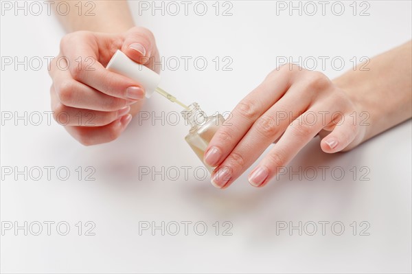 Close up of woman's hands holding nail polish, studio shot. Photo : Jan Scherders