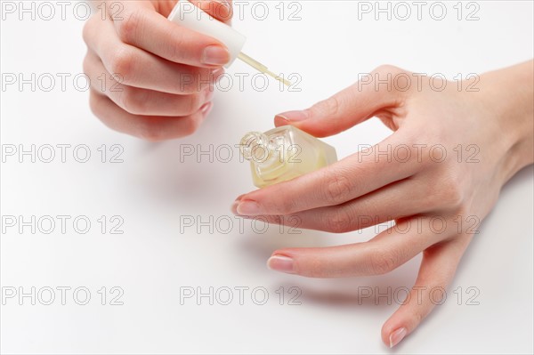 Close up of woman's hands holding nail polish, studio shot. Photo : Jan Scherders