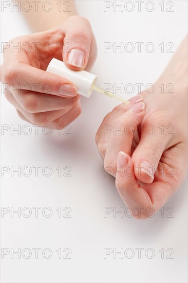 Close up of woman's hands painting fingernails, studio shot. Photo : Jan Scherders