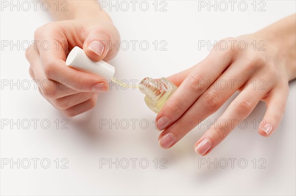 Close up of woman's hands holding nail polish, studio shot. Photo : Jan Scherders