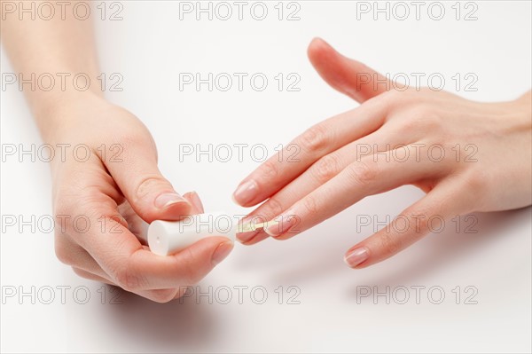 Close up of woman's hands painting fingernails, studio shot. Photo : Jan Scherders