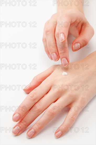 Close up of woman's hands applying moisturizer, studio shot. Photo : Jan Scherders